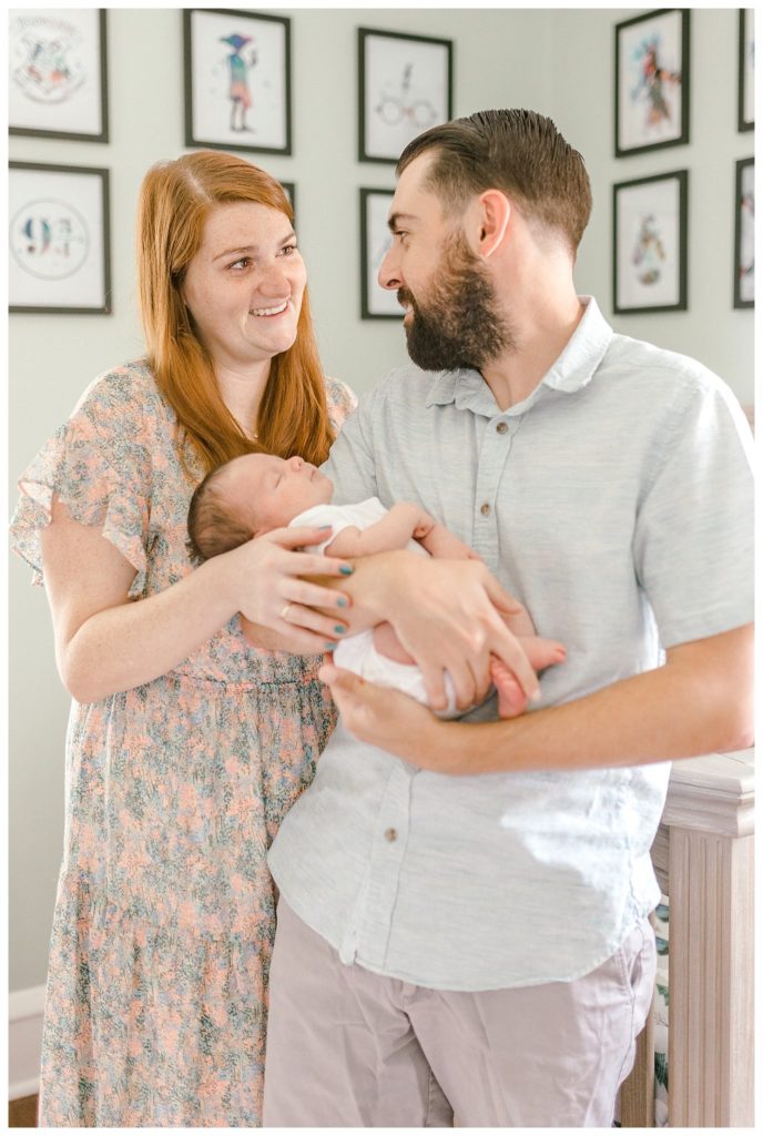 "mom and dad with baby in nursery"
